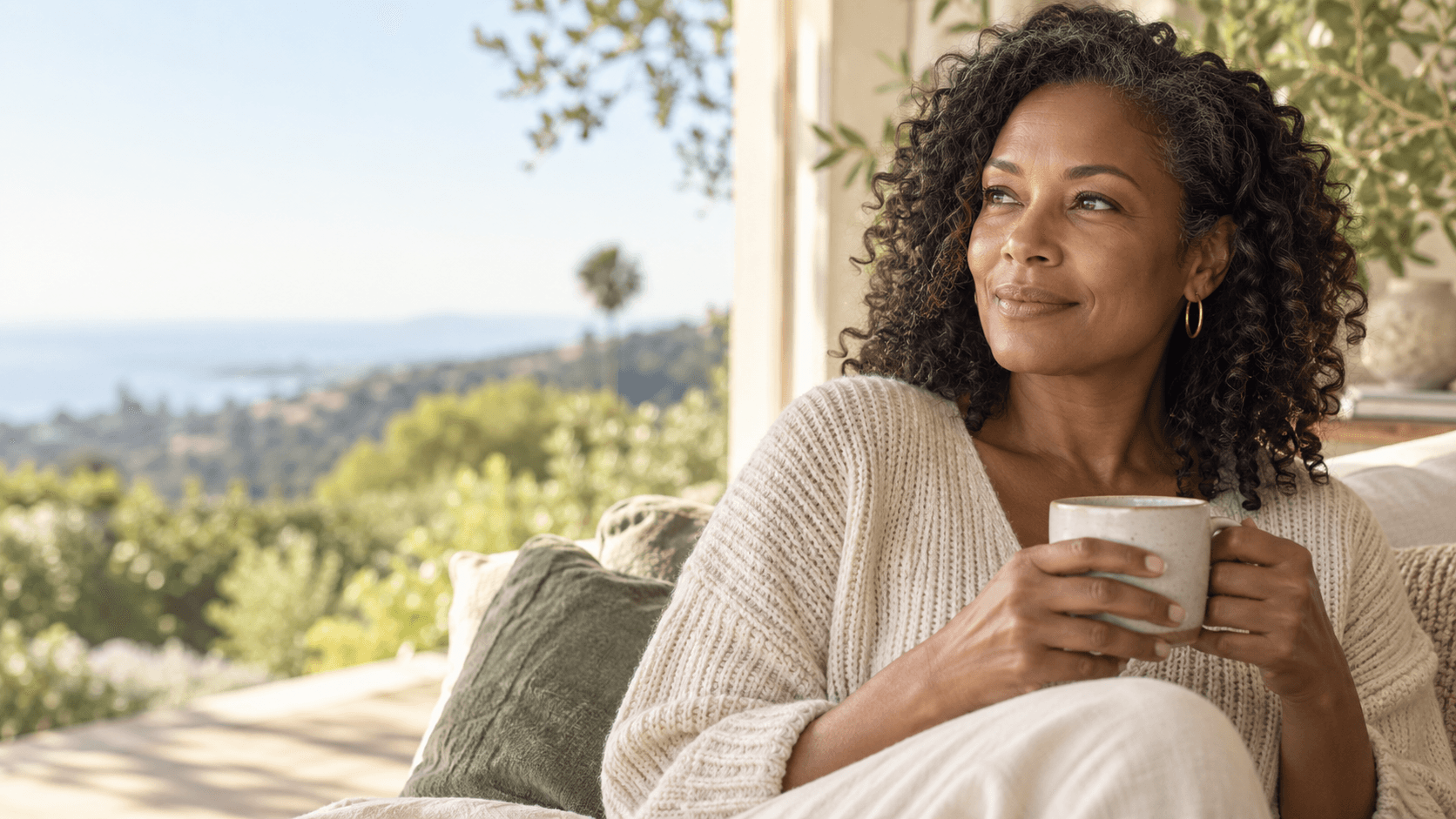 Adult woman holding a ceramic cup beside a bright window